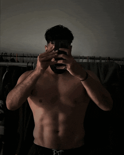 a shirtless man is taking a picture of himself with his phone