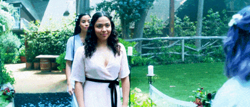 a woman in a pink dress is standing next to two other women in blue dresses .