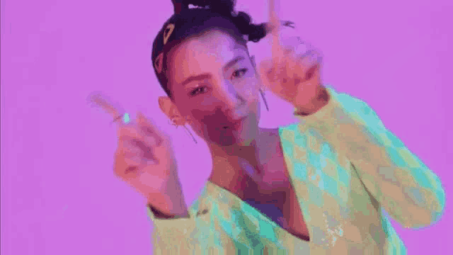 a woman is pointing at the camera with her fingers while wearing a green top and earrings .