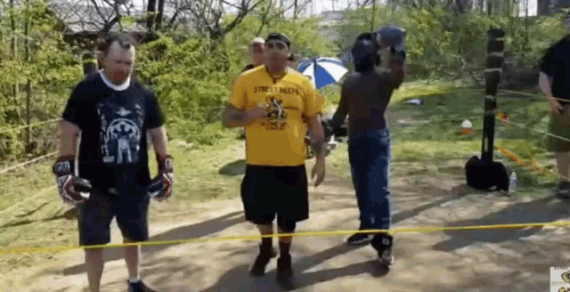 a man in a yellow shirt that says street mafia walks down a path