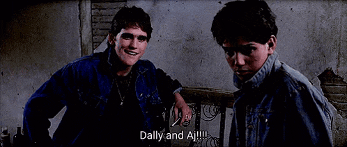 two young men are standing next to each other and one of them is talking about dally and aj .