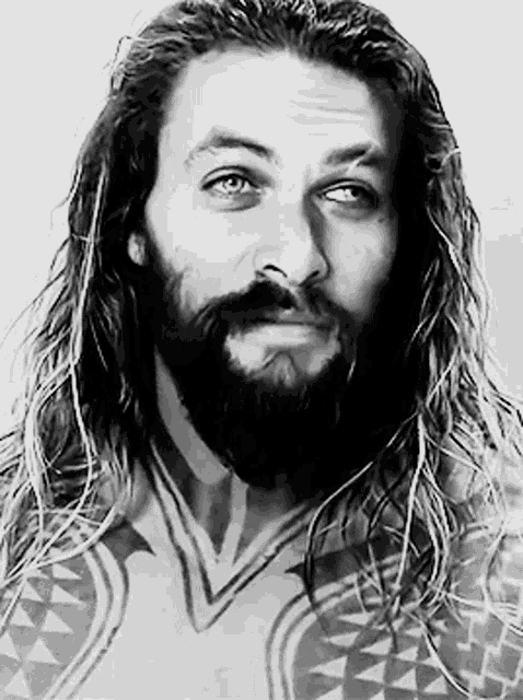 a man with long hair and a beard has a tattoo on his chest