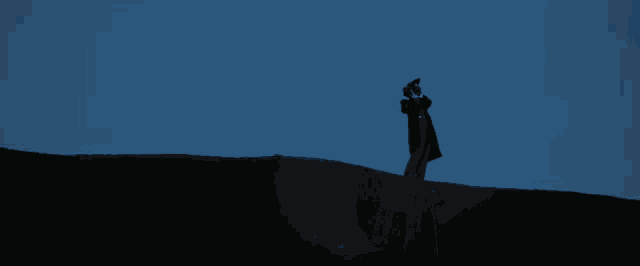 a man in a black coat is standing on a hill looking through binoculars