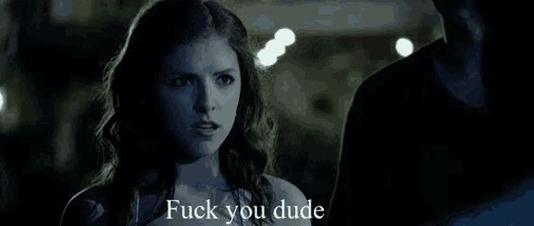 a woman is standing next to a man in a dark room and says `` fuck you dude '' .