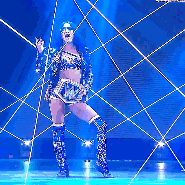 a woman in a wrestling outfit is standing on a stage holding a wrestling belt .