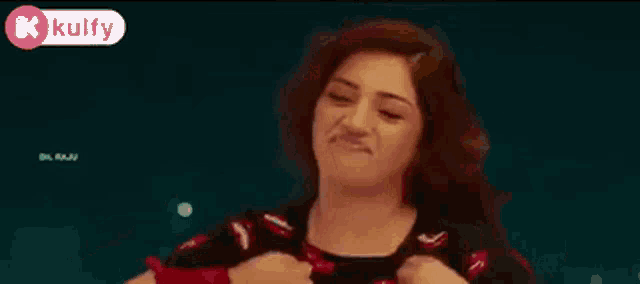 a woman is making a funny face with her arms outstretched while wearing a black shirt with red lips on it .