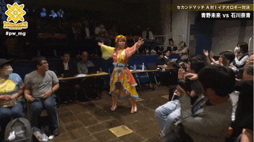a woman in a colorful dress is dancing in front of a crowd with the hashtag #pw_mg on the bottom