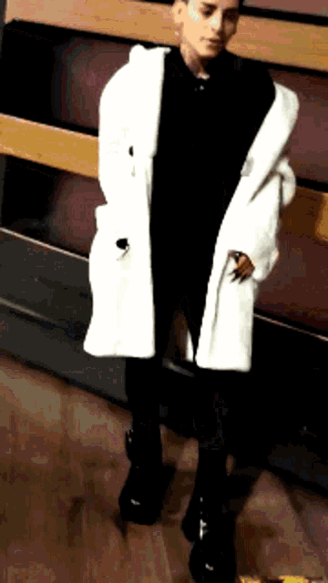 a man wearing a white coat and black pants