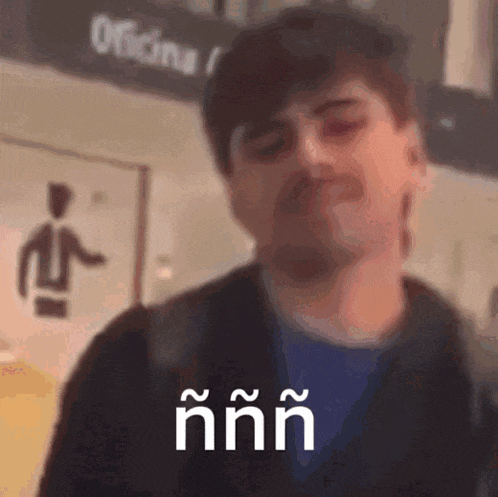 a man with a beard is standing in front of a sign that says oficina on it .