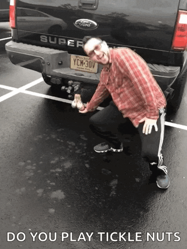 a man is kneeling in front of a ford super pickup truck