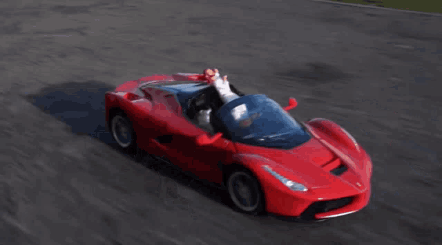 a person is sitting in a red sports car with their arm out the window