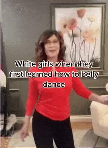 a woman in a red shirt and black pants is dancing in front of a picture of flowers .