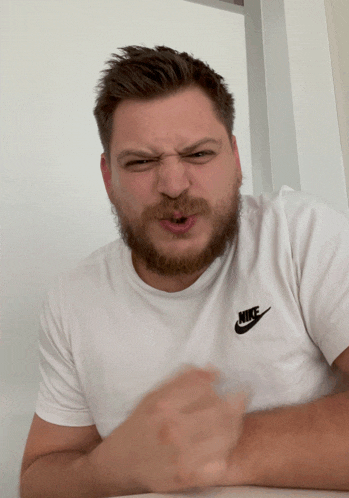 a man wearing a white nike t-shirt is making a funny face