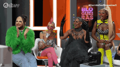 a group of drag queens sitting in front of a screen that says blo guei ras