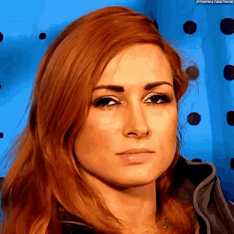 a close up of a woman 's face with red hair in front of a blue background with polka dots .