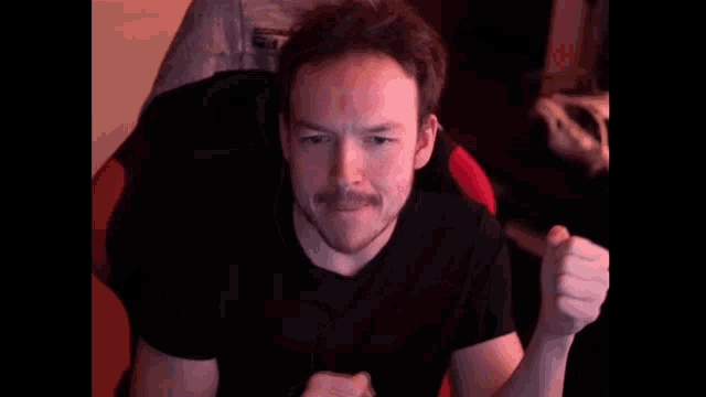 a man in a black shirt is sitting in a red chair