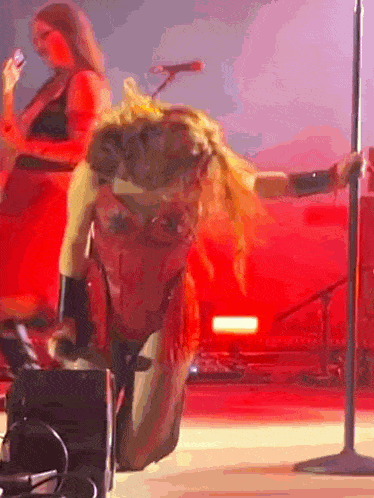 a woman is kneeling down in front of a microphone on a stage