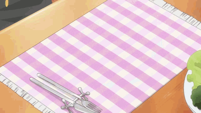 a purple and white checkered place mat with silverware and a plate of vegetables