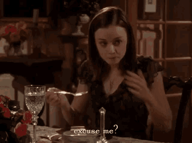 a woman is sitting at a table with a bowl of food and a glass of water and says excuse me ?