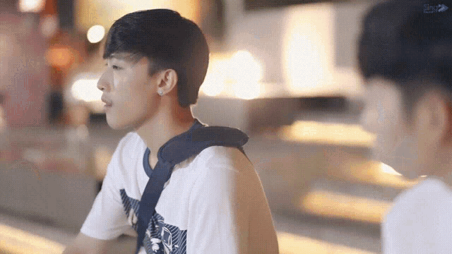 two young men are sitting next to each other on a sidewalk .