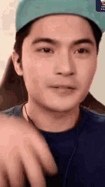 a close up of a man wearing a hat and a blue shirt .