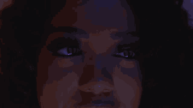a close up of a woman 's eyes with purple glowing eyes