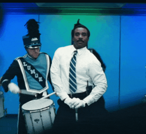 a man in a white shirt is playing a drum next to a man in a blue uniform that says lumon