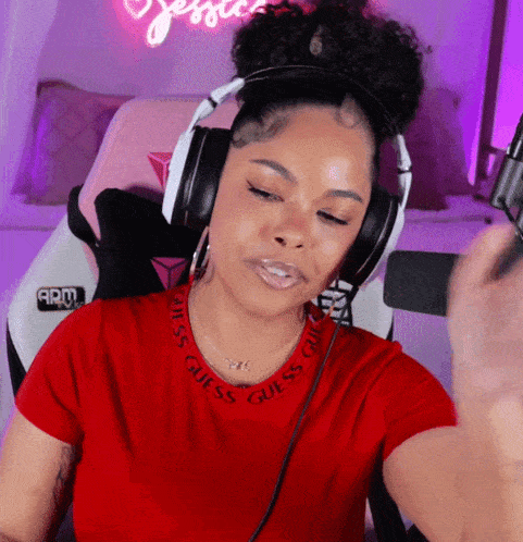 a woman wearing headphones and a red shirt with the word guess on it