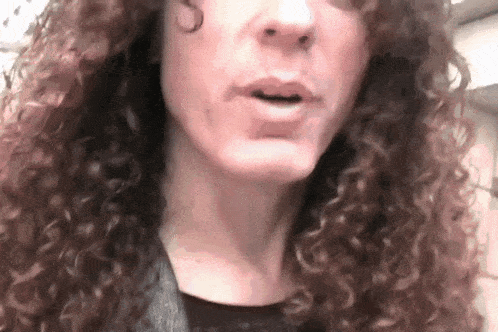 a woman with curly hair is speaking into a microphone