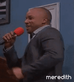 a man in a suit is singing into a microphone with meredith written on the bottom