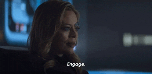 a woman is sitting in a dark room talking to another woman and says engage .