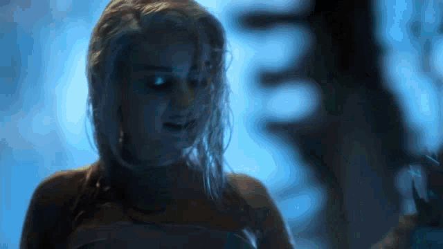 a woman with wet hair is standing in a dark room with a blue background .