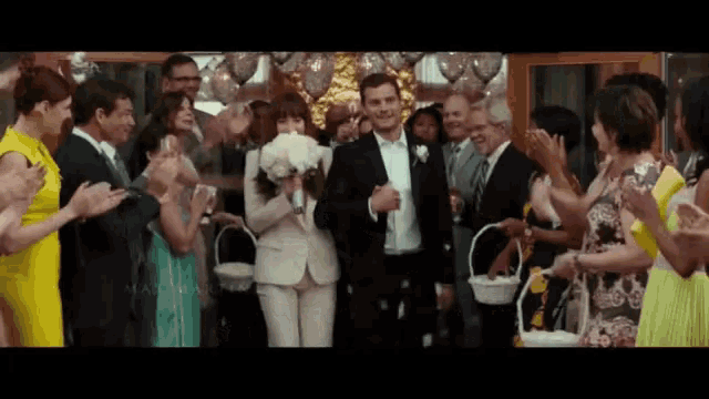 a bride and groom are walking down the aisle with their wedding party applauding them