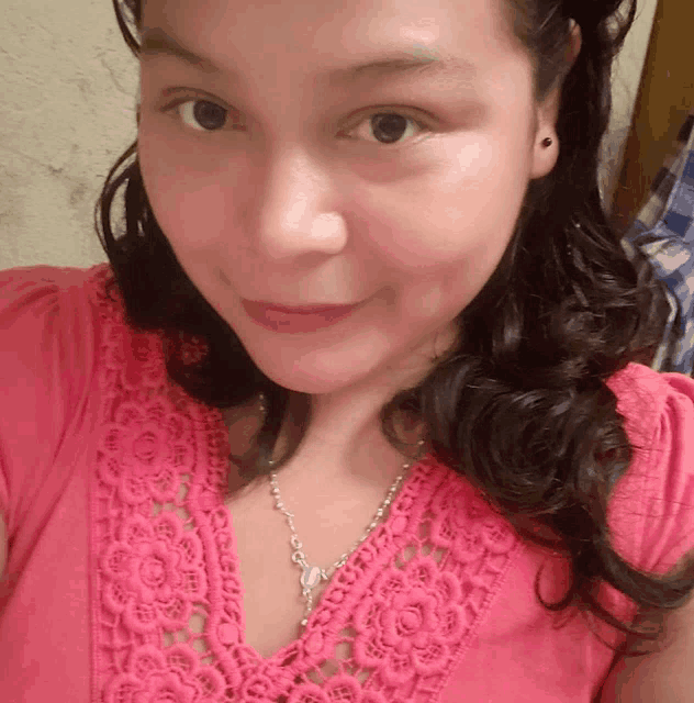 a woman wearing a pink lace top and a silver necklace