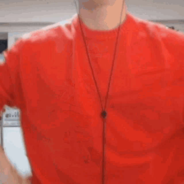 a man in a red sweater is standing in front of a microphone in a room .
