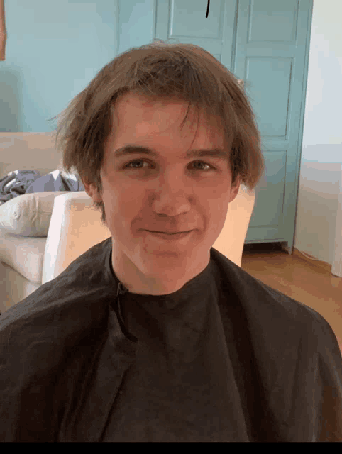 a young man is wearing a black cape and smiling