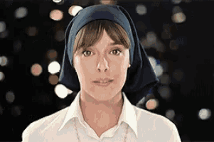a woman wearing a white shirt and a blue head scarf looks at the camera .