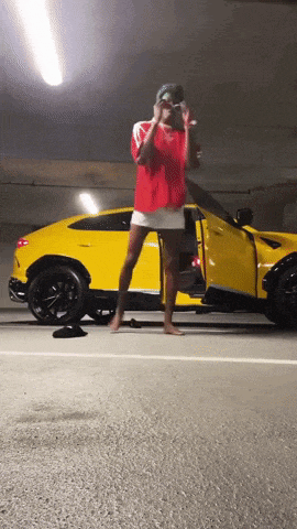 a woman standing in front of a yellow sports car
