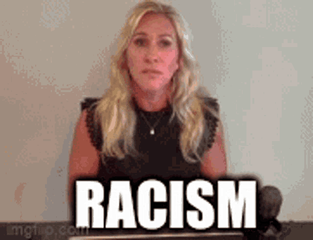 a woman is standing in front of a wall with the word racism written on it .