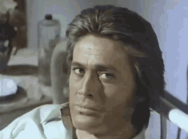 a man with long hair is sitting in a chair with his eyes closed