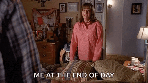 a woman in a pink shirt is standing in front of a bed .