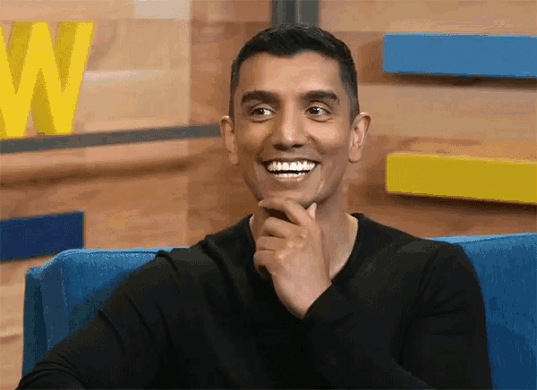 a man in a black shirt is smiling in front of a yellow w