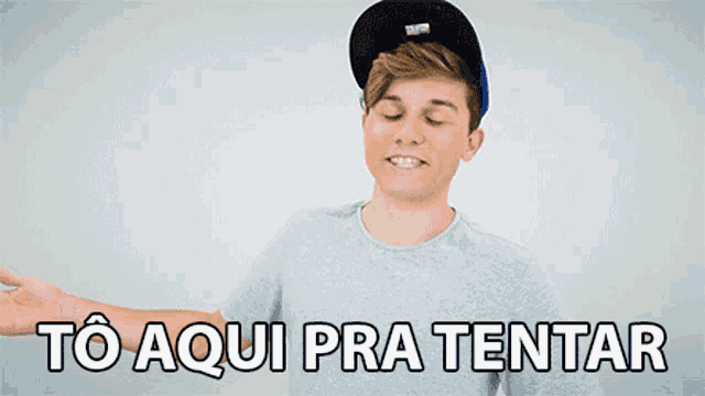 a young man wearing a hat and a grey shirt says to aqui pra tentar