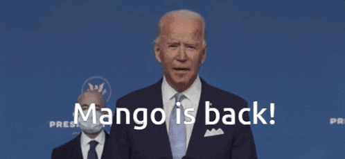 a man in a suit and tie is standing in front of a blue background that says mango is back