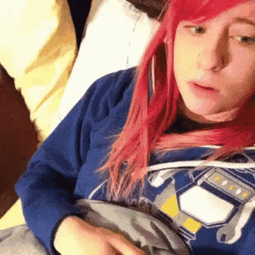 a girl with red hair is wearing a blue sweatshirt with a robot on it