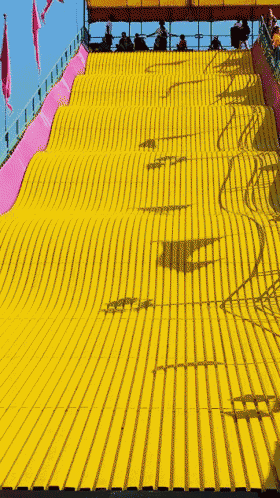 a group of people are riding down a yellow slide at a carnival