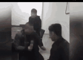 a group of men are standing in a room fighting each other .