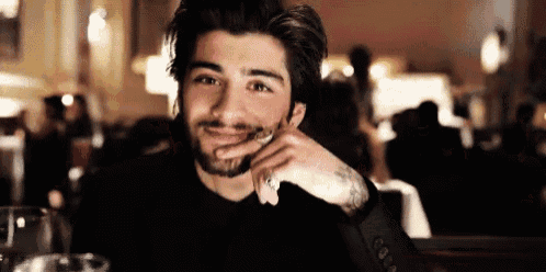 a man with a beard is sitting at a table in a restaurant and smiling .
