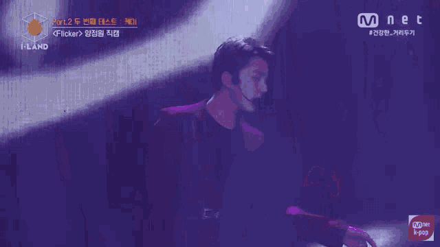 a man in a red suit is on a stage with a mnet logo behind him