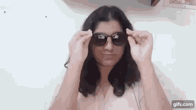 a woman is wearing sunglasses and making a funny face while looking at the camera .
